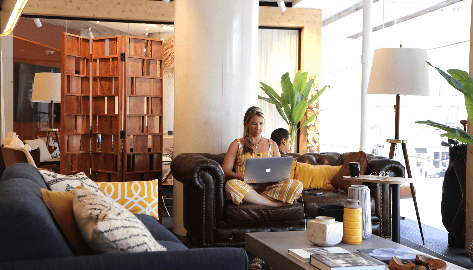 Avila Spaces member sitting on a sofa with a laptop