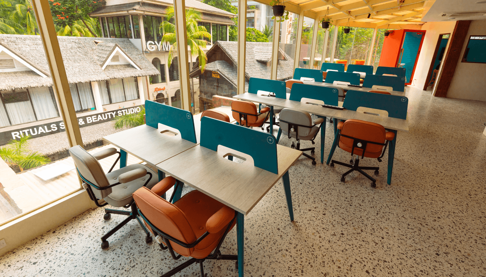 Bright coworking area at Neighbors & Nomads in El Nido with shared desks, ergonomic seating, and large windows overlooking the neighborhood.